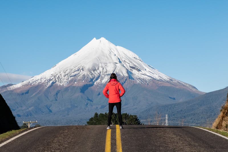 Person standing in the middle of road deep thinking in front of mountain peak. Person standing in the middle of road deep thinking in front of mountain peak.