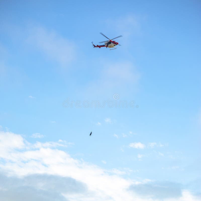 Person, die im Flug durch ein Seil auf einem Hubschrauber haning ist stockbild Person, die im Flug durch ein Seil auf einem Hubschrauber haning ist stockbild