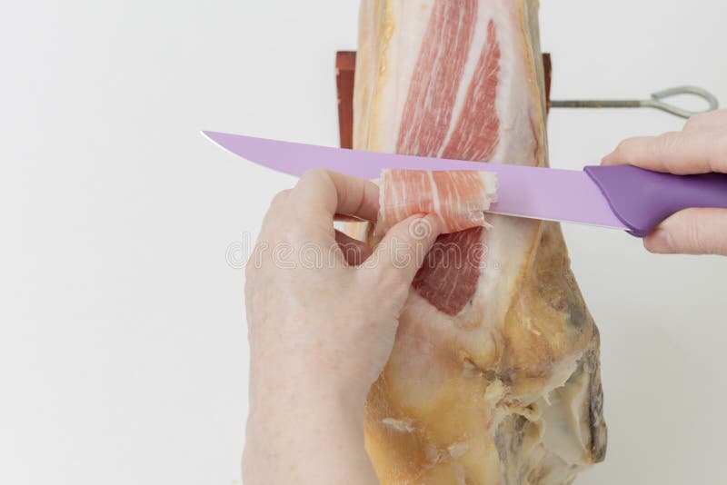 Person, die Schinkenscheiben mit einem Messer schneidet lizenzfreies stockfoto Person, die Schinkenscheiben mit einem Messer schneidet lizenzfreies stockfoto