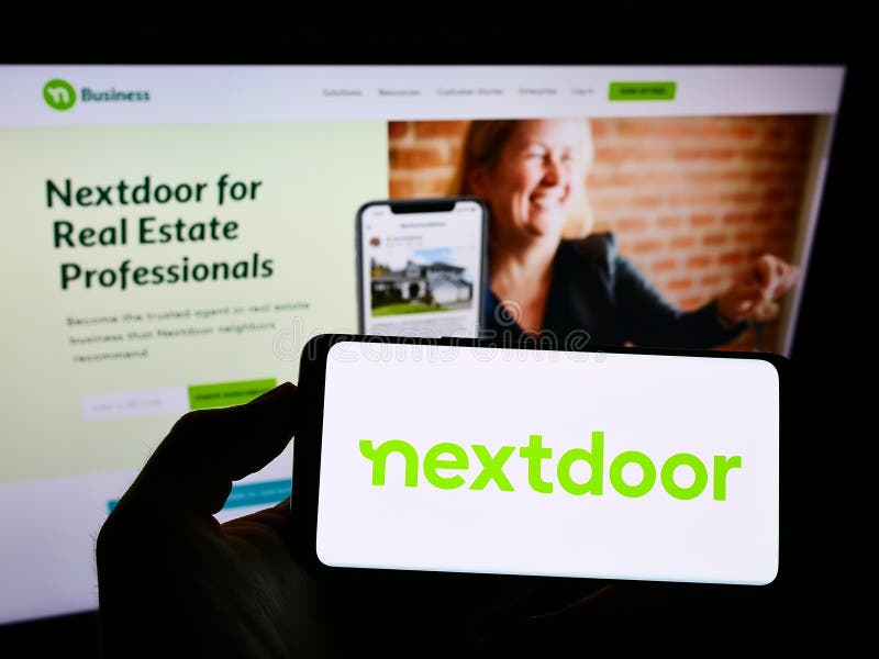 Person holding cellphone with logo of US social network company Nextdoor Inc. on screen in front of business webpage.