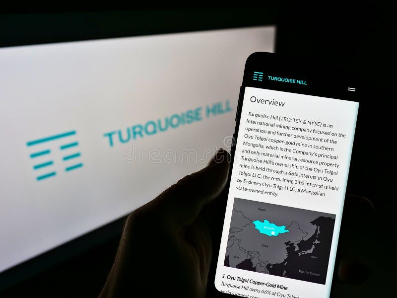 Person holding cellphone with website of Canadian mining company Turquoise Hill Resources Ltd on screen in front of logo.