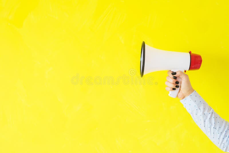Person holding megaphone on empty yellow background royalty free stock images