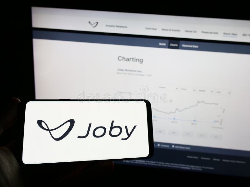 Stuttgart, Germany - 03-31-2023: Person holding mobile phone with logo of American eVTOL company Joby Aviation on screen in front of business web page. Focus on phone display.