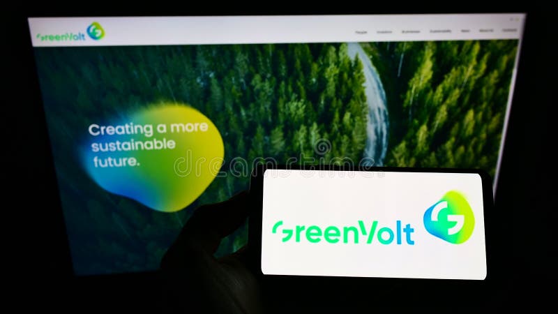 Person holding smartphone with logo of energy company Greenvolt Energias Renováveis SA on screen in front of website.