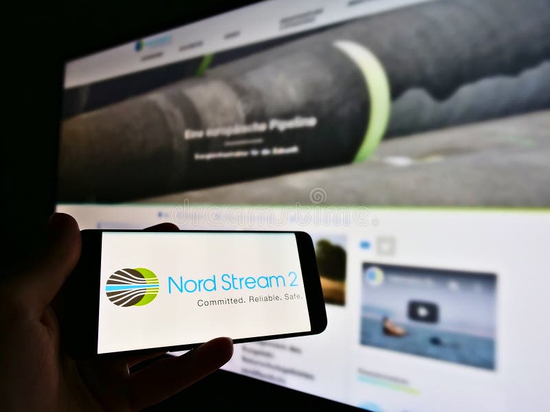 Person holding smartphone with logo of offshore natural gas pipeline project Nord Stream 2 in North Sea.