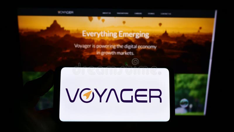 Person holding smartphone with logo of Philippine company Voyager Innovations Inc. on screen in front of website.