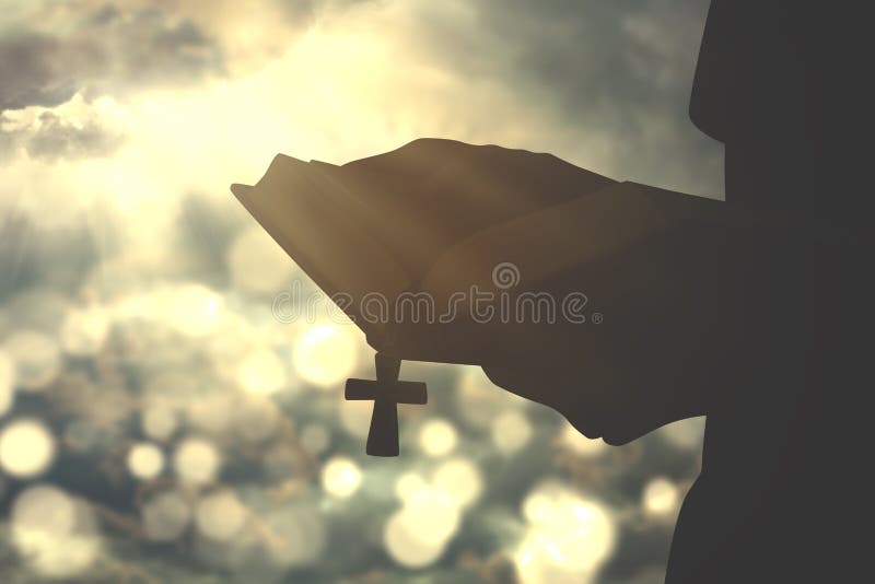 Person holds bible with crucifix symbol