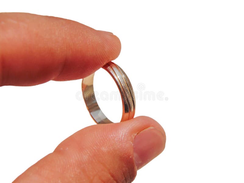 A Person Holds a Gold Wedding Ring between His Fingers Stock Image