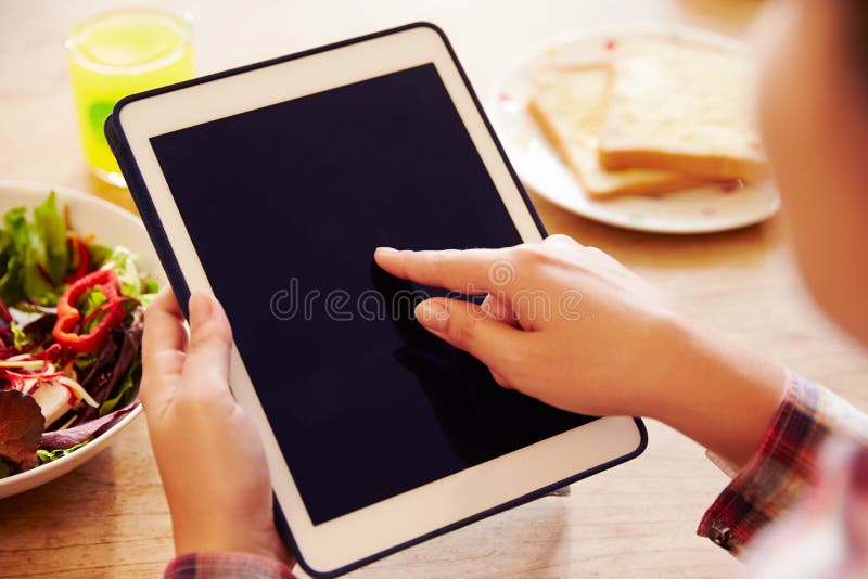 Person Looking at Digital Tablet Whilst Eating Lunch Stock Image