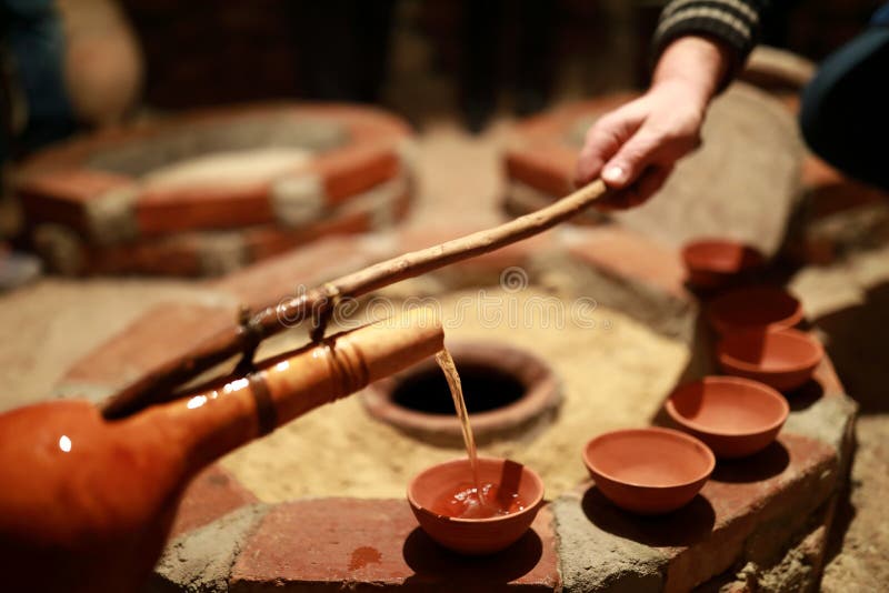 Person pouring wine from qvevri using Orshimo