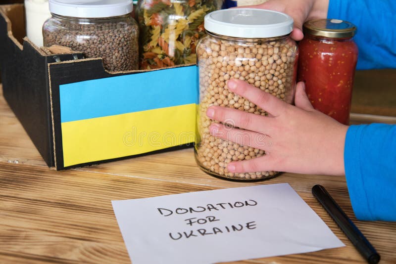 A Person Preparing a Box with Food To Donate To the War in Ukraine