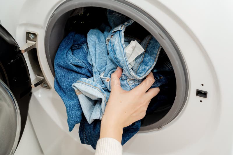Person Putting Jeans into the Drum of a Washing Machine, Front View