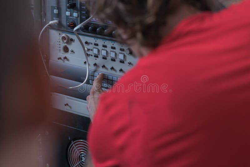 Person in red shirt pressing a button on a video switch panel or hub. High technology environment with a person operating a button royalty free stock photos