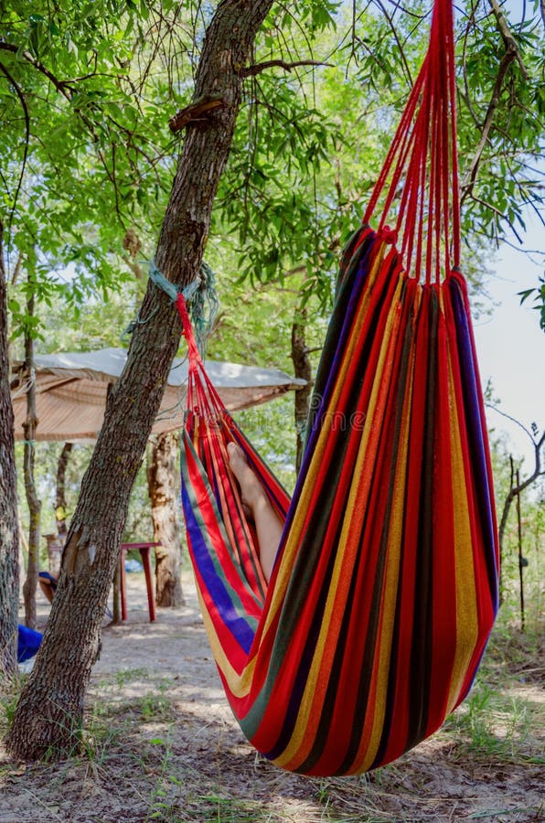 Person relaxing in the colorful hammock in tree`s shadow on hot sunny day. Lazy time royalty free stock photos