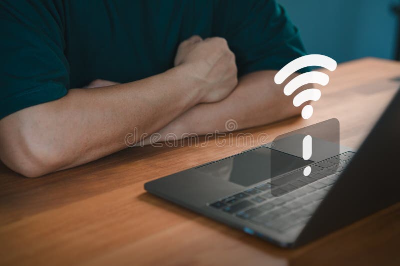 Person sit in front of a laptop displaying a Wi-Fi error symbol, indicating internet connectivity issues. stock photos