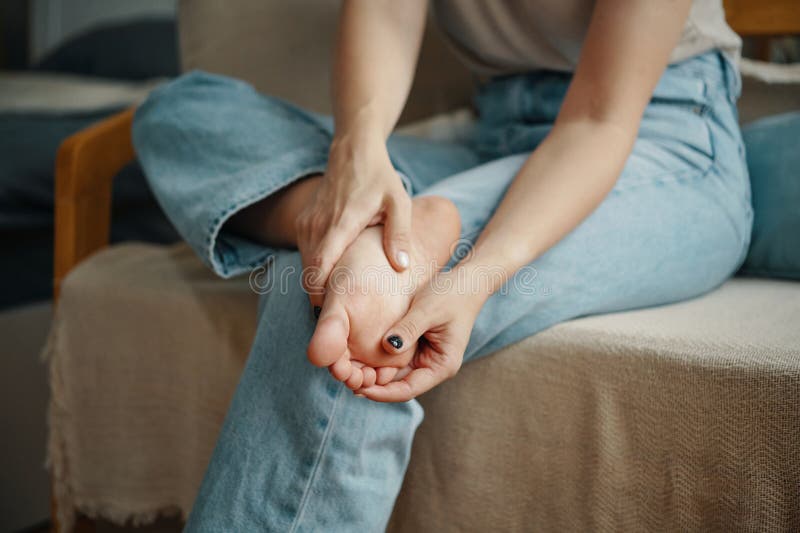 Massaging Aching Foot on Comfortable Chair stock photo