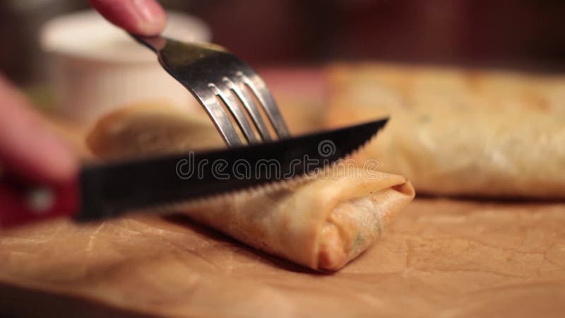 Person slicing a spring roll.