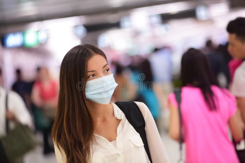 Person wearing protective mask against transmissible infectious diseases and as protection against pollution and the flu. Asian woman commuter in airport public area. Person wearing protective mask against transmissible infectious diseases and as protection against pollution and the flu. Asian woman commuter in airport public area.