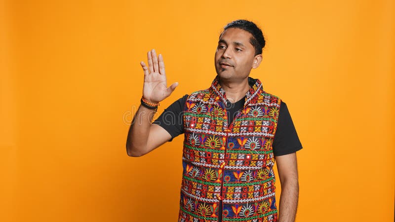 Person som gör sig lugn genom att visa studiens bakgrund. Indian som försöker stoppa kaotisk kamp genom att använda lugnande handgest för att sprida spänningar som gör fredlig lösning. lugnande personer som gör sig av med att lugna ner signaturgester med studiokamera