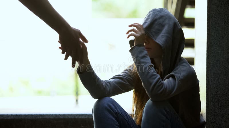 Person stretching helping hand to lonely depressed teen girl, support and aid, stock photo. Person stretching helping hand to lonely depressed teen girl, support and aid, stock photo