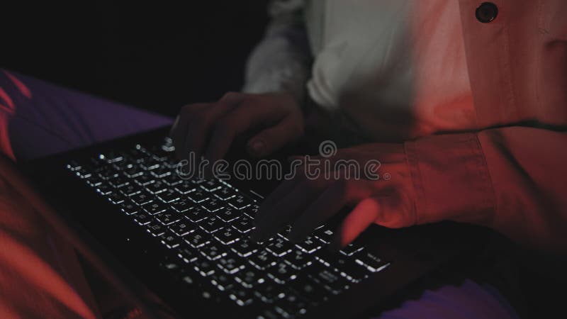 Person typing on a laptop in a dimly lit room creates a focused and productive atmosphere during late-night work or study session royalty free stock photos