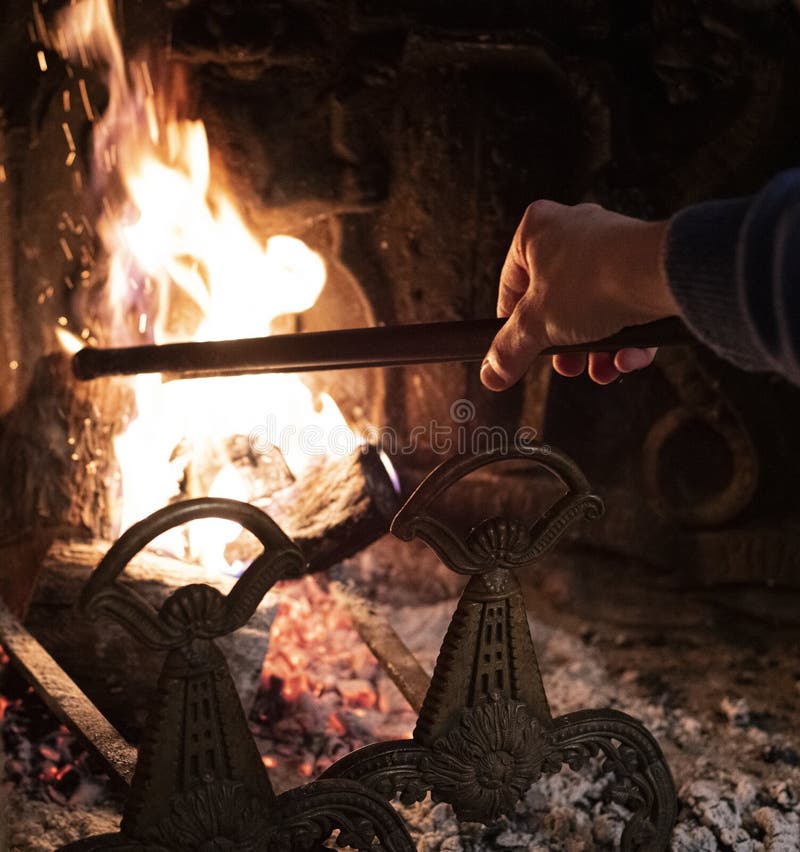 Person using a fire iron to stoke the flames