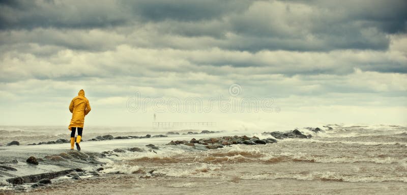 Ampio angolo di visualizzazione di causeway oltre mare in tempesta sotto cloudscape con la persona che cammina in primo piano.