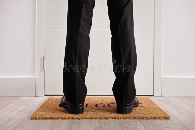 Persona che sta su uno zerbino davanti ad a porta chiusa