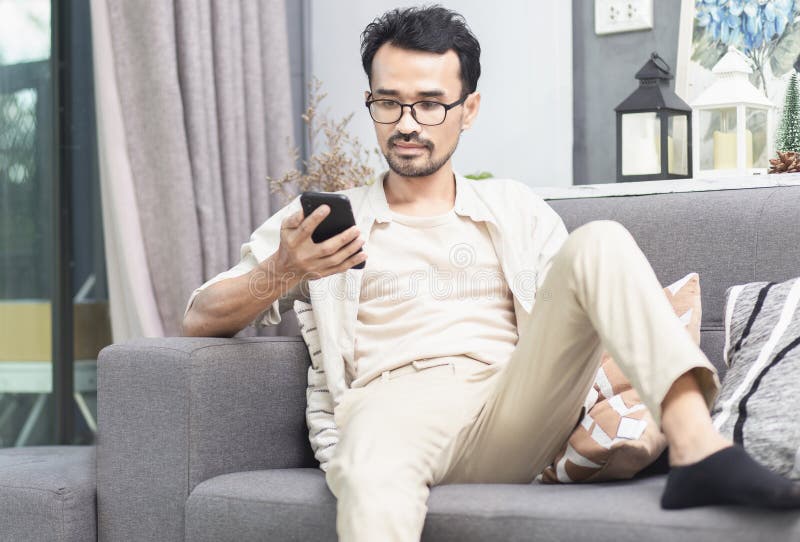 Persona che usa smartphone con applicazioni online social media durante la seduta a casa fotografia stock