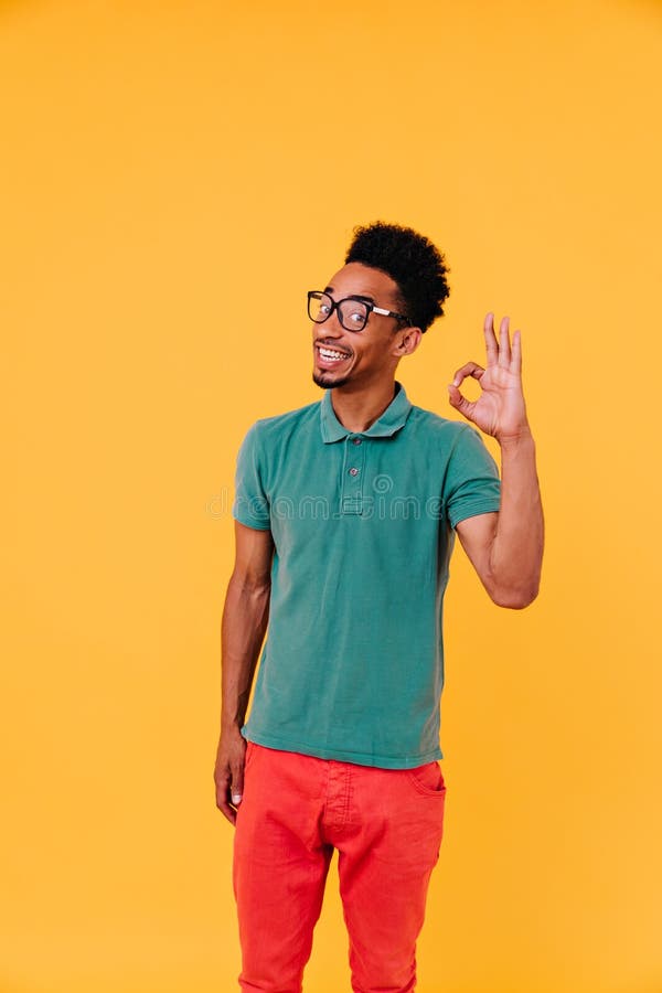 Persona emozionata con capelli divertenti in posa con segno d'ok. foto di un ragazzo africano emozionante in gla fotografia stock libera da diritti