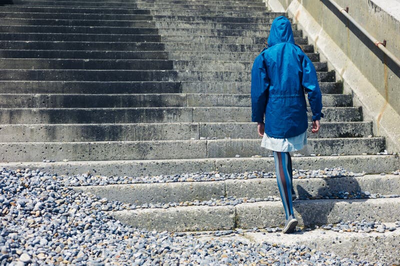 Persona en chaqueta azul que camina encima de las escaleras afuera imágenes de archivo libres de regalías Persona en chaqueta azul que camina encima de las escaleras afuera imágenes de archivo libres de regalías