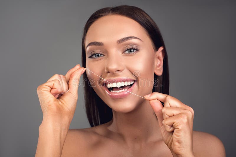 Persona femenina alegre que usa la seda dental imágenes de archivo libres de regalías Persona femenina alegre que usa la seda dental imágenes de archivo libres de regalías