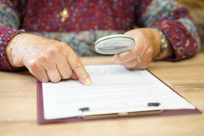 Elderly person with magnifying glass checking document . Elderly person with magnifying glass checking document .