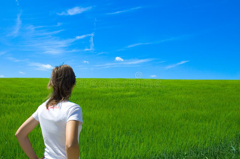 Person looking at bright green field under blue sky with clouds. Person looking at bright green field under blue sky with clouds