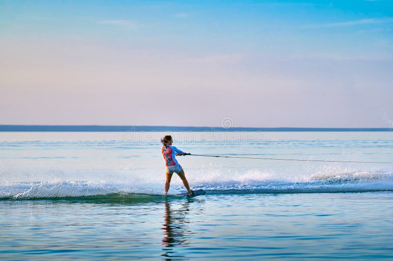 Persona que practica surf de la mujer con los rollos rojos del pelo en el tablero en una superficie plana del agua fotografía de archivo Persona que practica surf de la mujer con los rollos rojos del pelo en el tablero en una superficie plana del agua fotografía de archivo