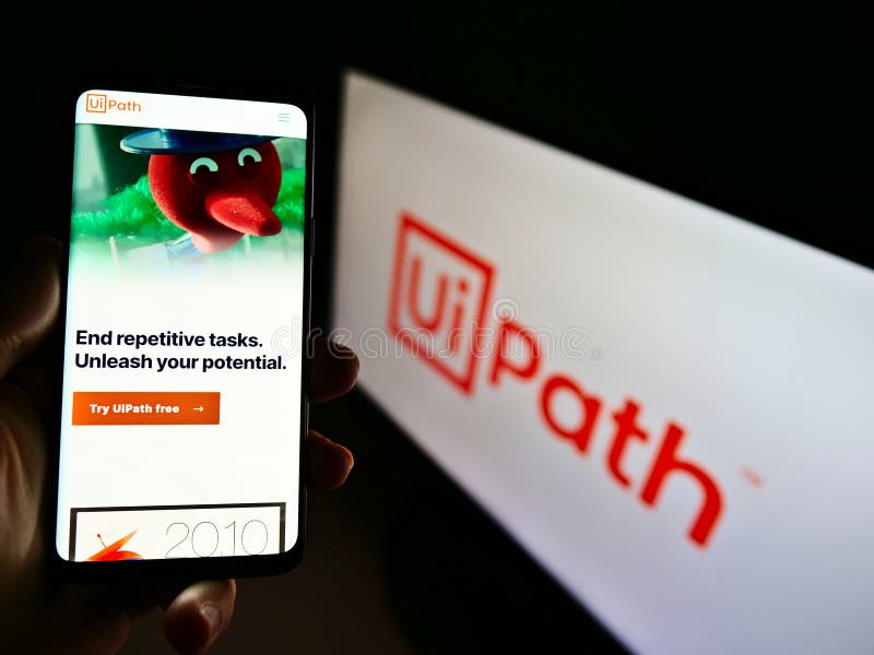 Persona que tiene teléfono móvil con sitio web de la empresa de desarrollo de software uipath inc. en pantalla delante del logotip fotos de archivo