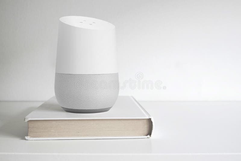 Personal assistant loudspeaker on a white wooden shelf of a smart home living room. Next, a book. Empty copy space royalty free stock image