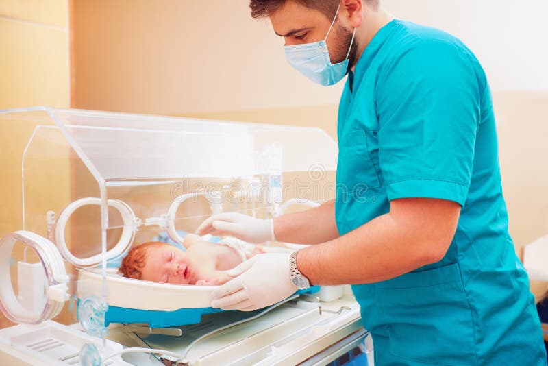 Personal médico que toma cuidado del bebé recién nacido en incubadora infantil fotografía de archivo libre de regalías Personal médico que toma cuidado del bebé recién nacido en incubadora infantil fotografía de archivo libre de regalías
