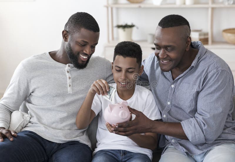 Black Preteen Boy With Father And Grandfather Putting Money To Piggybank