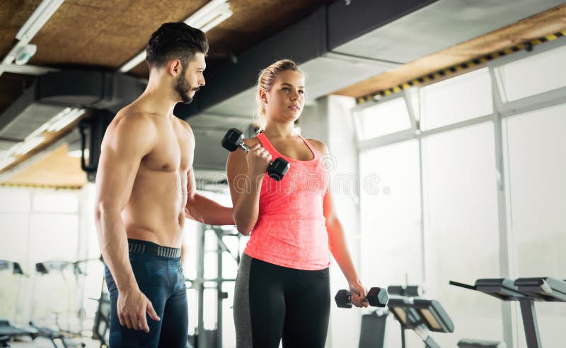 Personal Trainer Helping Young Woman With Exercises For Biceps Stock 