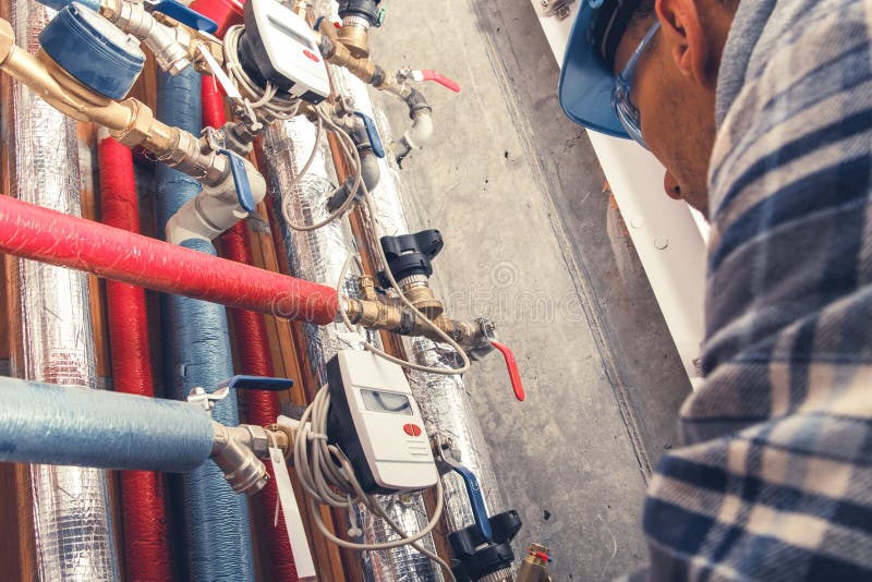 Personale qualificato che esamina il sistema idraulico in un impianto industriale durante il giorno immagine stock libera da diritti