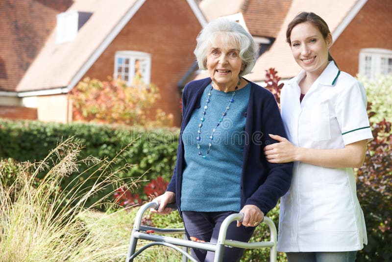 Personale sanitario che aiuta donna senior a camminare in giardino facendo uso della struttura di camminata fotografia stock libera da diritti Personale sanitario che aiuta donna senior a camminare in giardino facendo uso della struttura di camminata fotografia stock libera da diritti