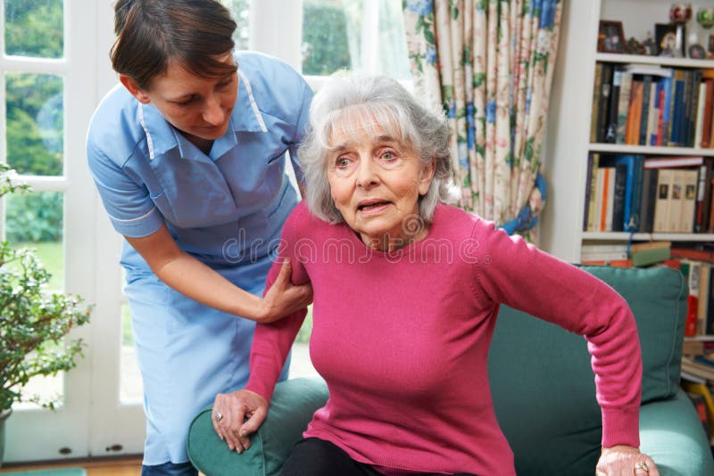 Personale sanitario che aiuta donna senior dalla sedia fotografie stock Personale sanitario che aiuta donna senior dalla sedia fotografie stock