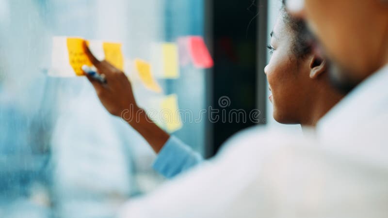 Personas de negocios que toman notas de recordatorio a bordo durante la conferencia fotografía de archivo libre de regalías