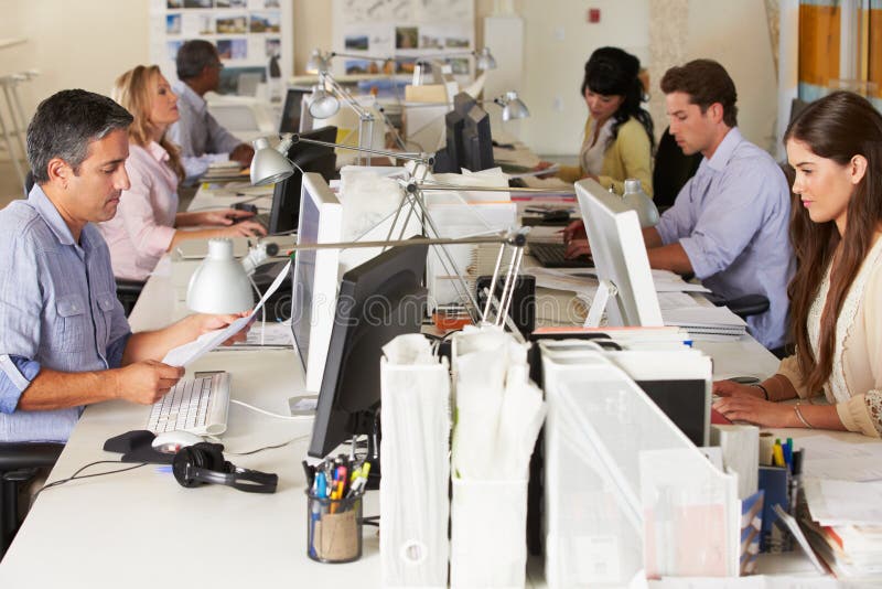 Personas que trabajan en los escritorios en oficina ocupada imagen de archivo Personas que trabajan en los escritorios en oficina ocupada imagen de archivo