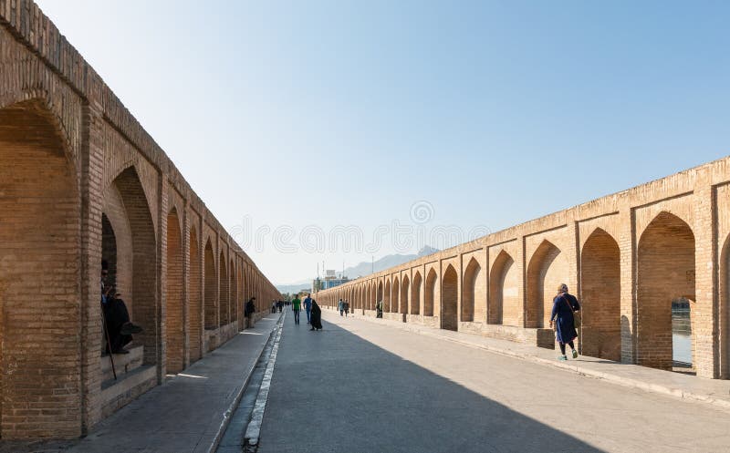 Isfahan, Iran - November 2, 2019: People walking along walkway of Si-o-Se Pol (Bridge of 33 Arches or Allahverdi Khan Bridge) on Zayanderud in Isfahan, Iran. Architectural masterpiece and heritage. Isfahan, Iran - November 2, 2019: People walking along walkway of Si-o-Se Pol (Bridge of 33 Arches or Allahverdi Khan Bridge) on Zayanderud in Isfahan, Iran. Architectural masterpiece and heritage.