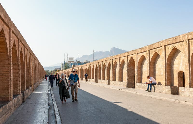 Isfahan, Iran - November 2, 2019: People walking along walkway of Si-o-Se Pol (Bridge of 33 Arches or Allahverdi Khan Bridge) on Zayanderud in Isfahan, Iran. Architectural masterpiece and heritage. Isfahan, Iran - November 2, 2019: People walking along walkway of Si-o-Se Pol (Bridge of 33 Arches or Allahverdi Khan Bridge) on Zayanderud in Isfahan, Iran. Architectural masterpiece and heritage.