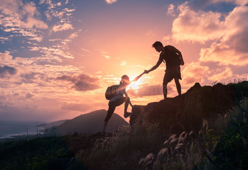 Persone che si aiutano a scalare una montagna all'alba. dare una mano.