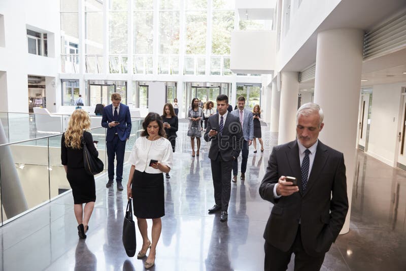 Businesspeople Using Technology In Busy Lobby Area Of Office. Businesspeople Using Technology In Busy Lobby Area Of Office