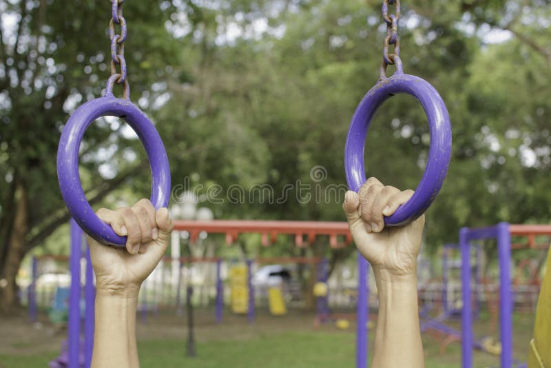 Personengriff das Blau, das öffentlich den Park der Übungsausrüstung im Freien hängt stockfotografie Personengriff das Blau, das öffentlich den Park der Übungsausrüstung im Freien hängt stockfotografie